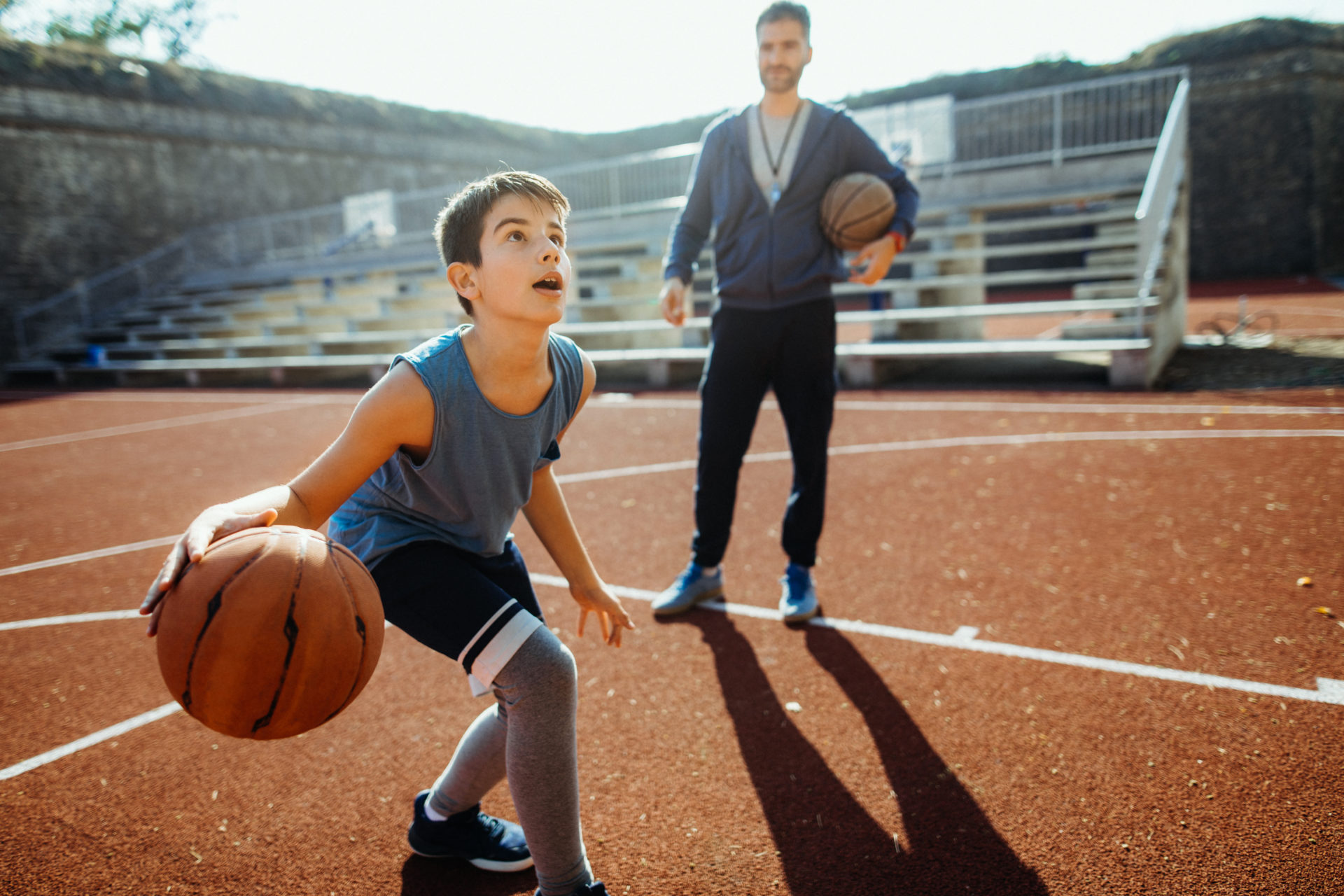 Photo of boy practicing is basketball with his coach